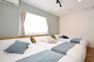 three beds in a room with a window at LAZULI Fukutsu in Fukuoka