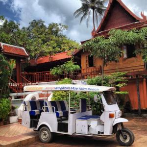 um carrinho de golfe estacionado em frente a uma casa em Harry's Bungalows em Mae Nam