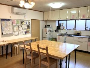 a kitchen with a wooden table and chairs in it at ゲストハウスわたうさぎ in Tsuruoka