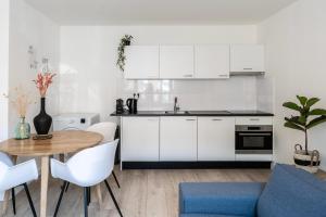 a kitchen with white cabinets and a table and chairs at Spacious Family Stay Eindhoven, Garden & Kitchen in Eindhoven