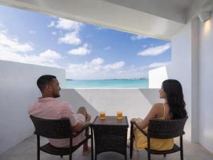 a man and woman sitting at a table with a view of the ocean at VOYAN Resort MiyakojimaーAZOMARE アゾマーレ in Miyako-jima