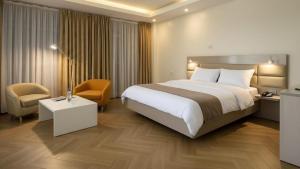a hotel room with a large bed and a chair at Golden Gate Hotel Hawassa in Āwasa +14 photos