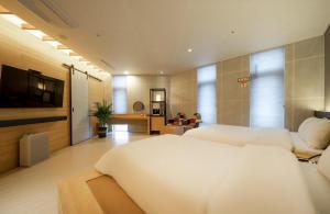 ein Schlafzimmer mit zwei Betten und einem Flachbildfernseher in der Unterkunft Naju Holius Hotel in Naju