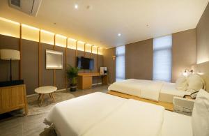 ein Hotelzimmer mit zwei Betten und einem Fernseher in der Unterkunft Naju Holius Hotel in Naju + 17 Fotos