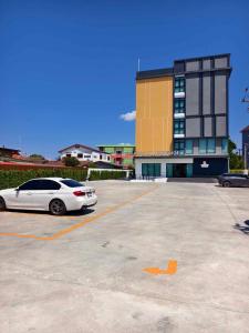 a white car parked in a parking lot in front of a building at Prajan Residence in Buriram