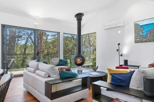 a living room with a couch and a fireplace at Architectural Beachfront Escape Yowani House in Tomakin