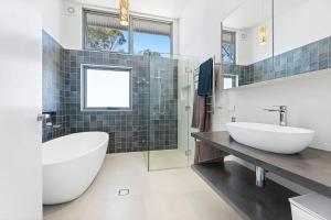 a bathroom with a large white tub and a sink at Architectural Beachfront Escape Yowani House in Tomakin