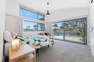 a bedroom with a bed and a couch and windows at Architectural Beachfront Escape Yowani House in Tomakin