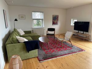 a living room with a green couch and a table at House direct to beach in Greve