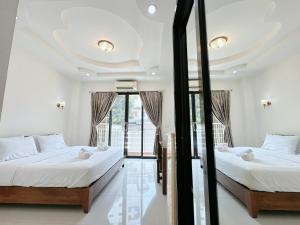two beds in a room with a window at เมืองเพ็ชร์ เกสต์เฮ้าส์ in Phetchaburi