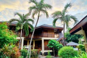 a house with palm trees in front of it at Alta Cebu Resort Mactan powered by Cocotel in Mactan