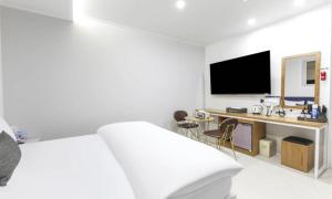 a white bedroom with a bed and a desk at Gimcheon Sweet Hotel in Kimch'ŏn