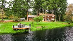 a wooden bridge over a river with a house at 4-Bedroom Chateau in Southern Washington- Luxurious Retreat with Pond & Creek in Amboy