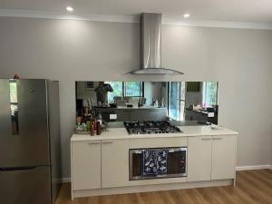 a kitchen with white cabinets and a stove top oven at Coalmine Beach Holiday Park in Walpole