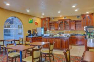 a kitchen with wooden cabinets and tables and chairs at Quality Inn & Suites Roswell North in Roswell