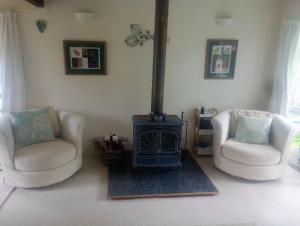 a living room with two chairs and a stove at Beside the lagoon - Waikanae Beach in Waikanae