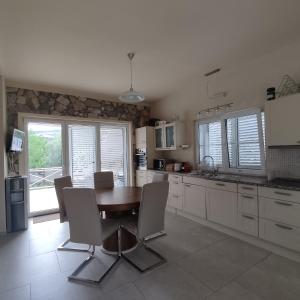 a kitchen with a wooden table and chairs and windows at Suntime villa Laguna in Bigova