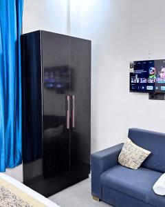 a black refrigerator in a living room with a blue couch at Barsana Suites in Vrindāvan