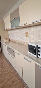 a kitchen with white cabinets and a microwave at Naparis Boutique in Eforie Sud