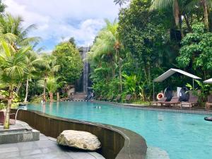a swimming pool in a resort with palm trees at Siloso Beach Resort - Sentosa in Singapore