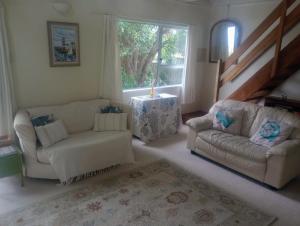 a living room with two couches and a table at Beside the lagoon - Waikanae Beach in Waikanae