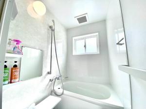 a white bathroom with a tub and a sink at バンビホーム青森中央 in Aomori