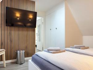 two beds in a room with a tv on the wall at Haus Meereswoge, Duhnen in Cuxhaven