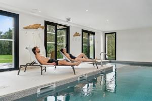 two people laying in chairs next to a swimming pool at MH Hôtel & Spa Arradon - Golfe du Morbihan in Arradon
