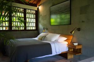 a bedroom with a bed and a large window at Sejati Boutique Hotel Uluwatu in Uluwatu