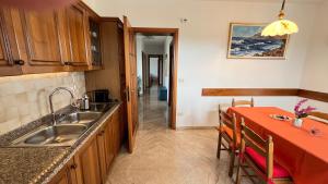 a kitchen with a sink and a red table with chairs at La Casa di Ekeko in Vivaro