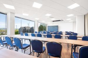 a conference room with long tables and blue chairs at Hotel Arena Maribor in Maribor
