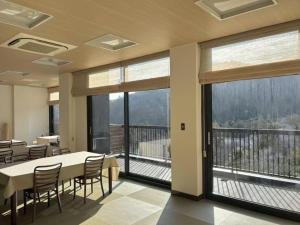 a dining room with a table and chairs and large windows at 光沙の森 in Hakone