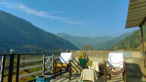a balcony with two chairs and a view of mountains at Dev Niwas in Nākuri