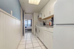 a kitchen with white cabinets and a tile floor at Spacious Beach Condo Double Suite for Couples Getaway in Myrtle Beach