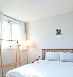 a white bedroom with a bed and a window at SlowNight, Suwon in Suwon