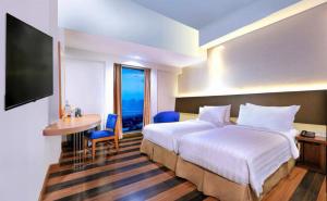 a hotel room with a bed and a desk and a television at Aston Palembang Hotel & Conference Centre in Palembang +42 photos
