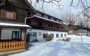 a house with a snow covered yard in front of it at Pension Max Schraml in Grundlsee