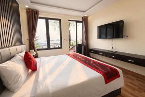 a bedroom with a large bed with a flat screen tv at LePont Cat Ba Bungalow in Cat Ba