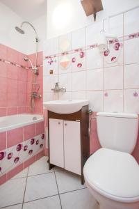 a pink bathroom with a toilet and a sink at Wspólna Apartment in Warsaw