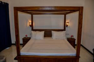 a bedroom with a large bed with a wooden frame at Vishu villa in Galle +4 photos
