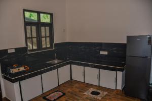a kitchen with black counter tops and a refrigerator at Vishu villa in Galle