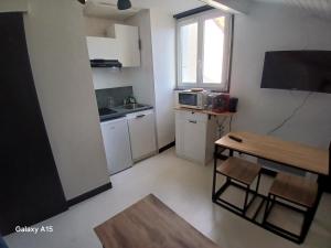 a small kitchen with white cabinets and a table at studio coralie in Saint-Flour +2 photos