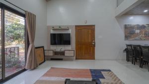 a living room with a television and a door at Shri Laxmi Narayan Bungalow in Mahabaleshwar