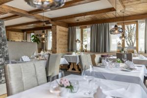 a restaurant with white tables and chairs and windows at Sunstar Hotel Klosters in Klosters