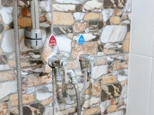 a bathroom with two faucets and a stone wall at เมืองเพ็ชร์ เกสต์เฮ้าส์ in Phetchaburi