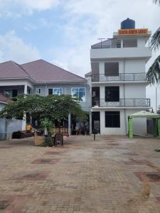 a large white building with a tree in front of it at KimyaKimya Pub & Lodge in Dar es Salaam