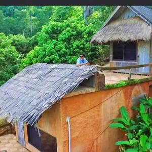 a man sitting on the roof of a house at Akha Hill House in Ban Doi Hang +30 photos