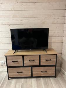 a flat screen tv sitting on top of a wooden dresser at Maisonnette chaleureuse, paisible & proche tram in Blanquefort