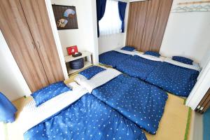 two beds in a bedroom with blue sheets with white polka dots at はなハウス 401 in Ginowan