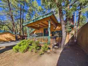 a house with a porch with a tree at Whispering Pine Cabins in Ruidoso